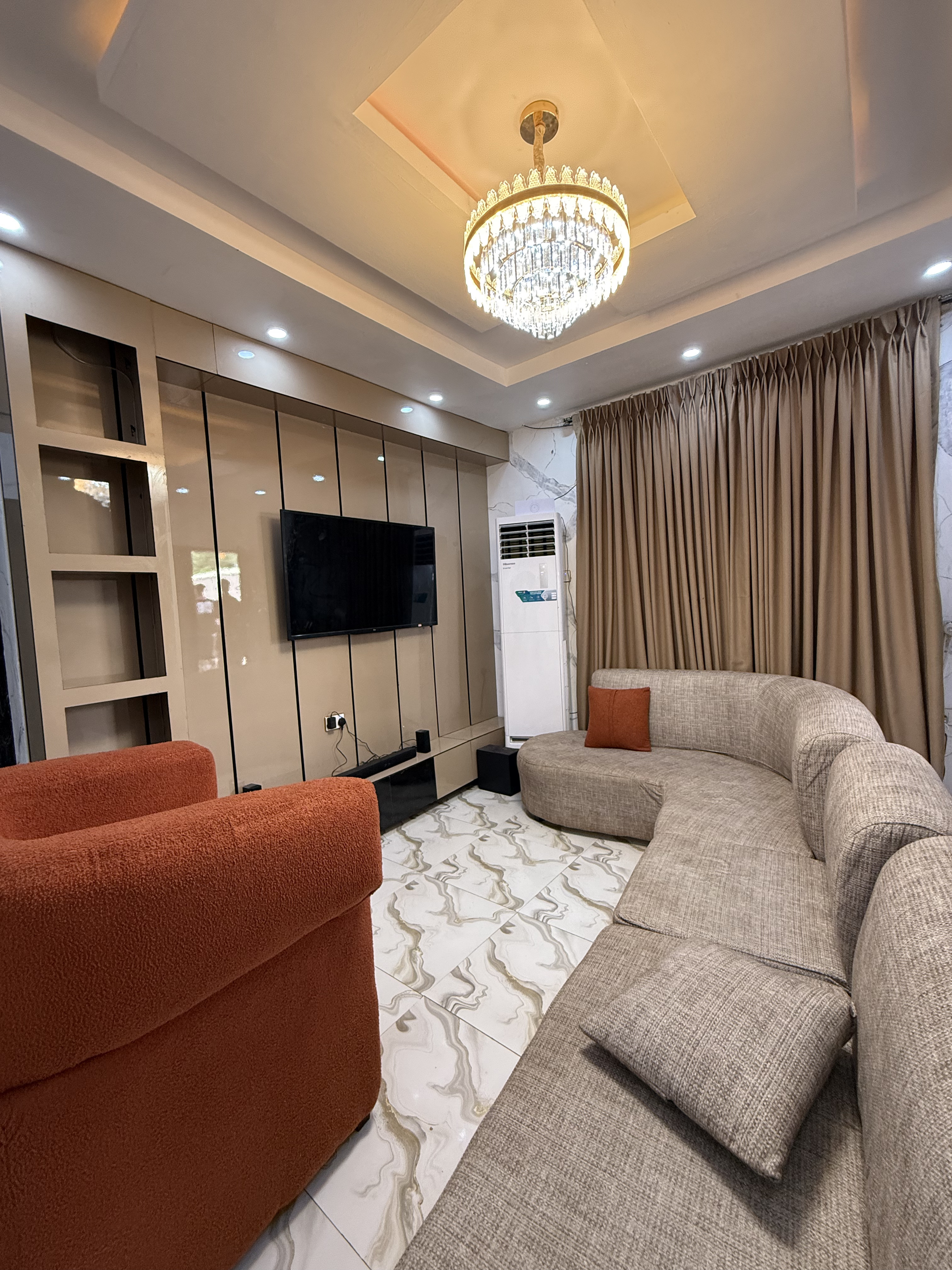 Sunlit living room with layered neutral textiles, a curved sofa and bespoke joinery